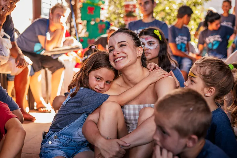Bárbara Maria Vieira sentada entre crianças sorridentes durante uma ação social